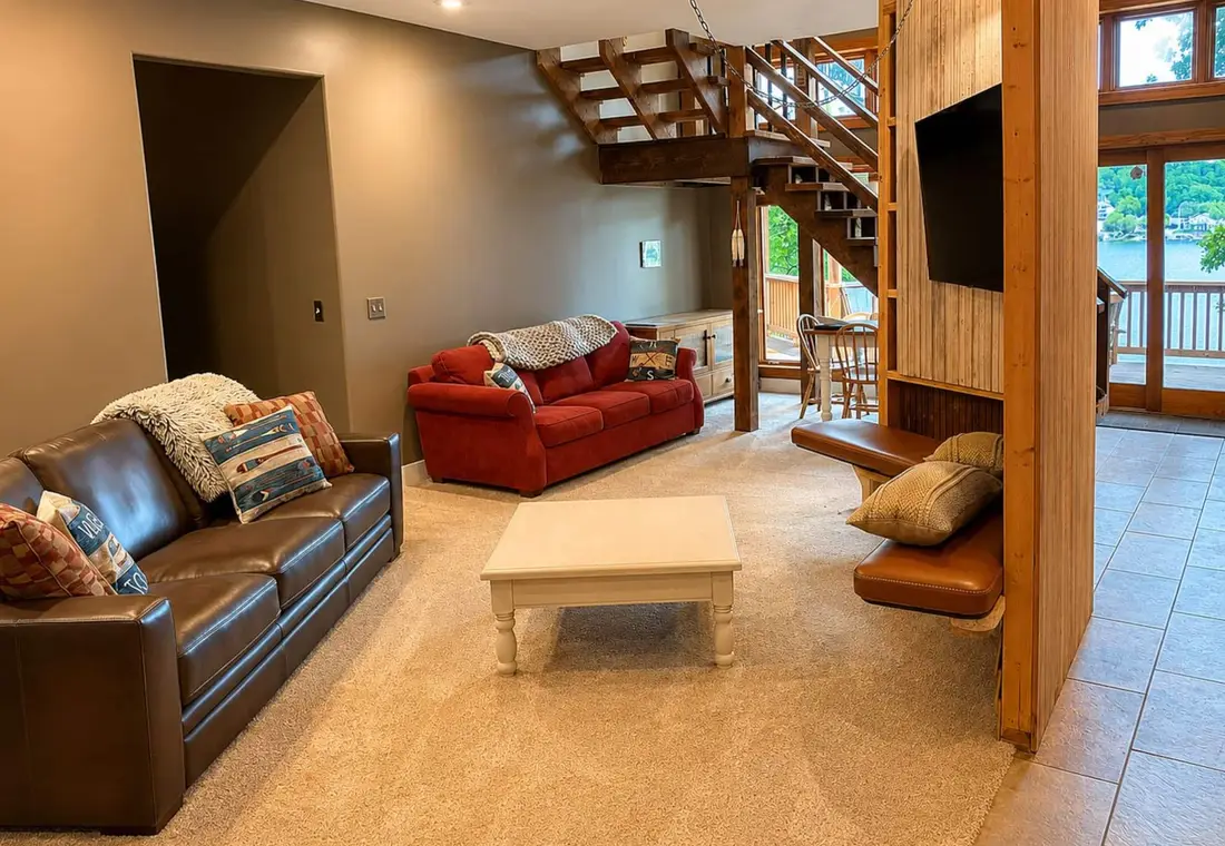 The lower-level lounge with sofas, a television and doors out to the lake