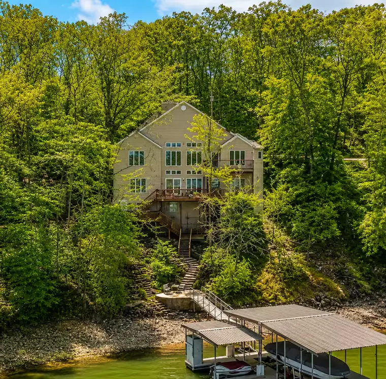 The house seen from the water, with its dock below and woods behind