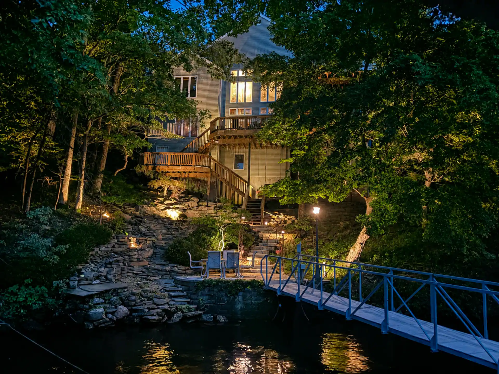 The house lit up at night, seen from the dock